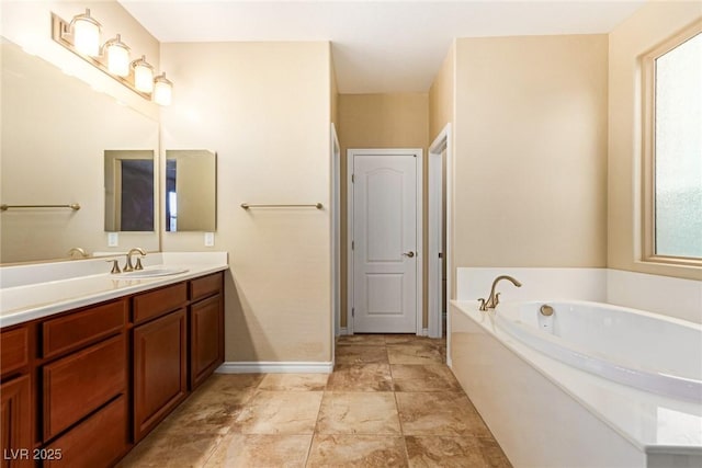 full bath featuring vanity, a bath, and baseboards