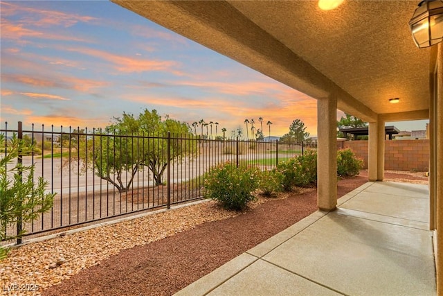 patio terrace at dusk featuring a fenced backyard