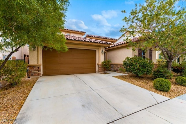 mediterranean / spanish-style house featuring concrete driveway, stone siding, a garage, and stucco siding