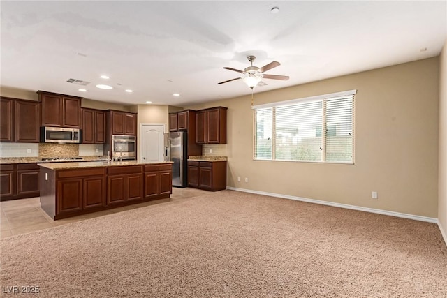 kitchen with open floor plan, tasteful backsplash, visible vents, and stainless steel appliances