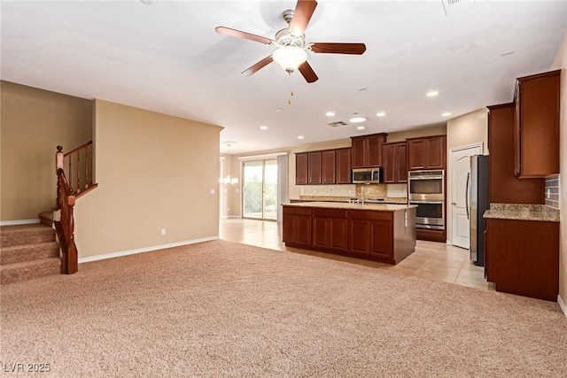 kitchen with open floor plan, light countertops, a ceiling fan, appliances with stainless steel finishes, and light colored carpet