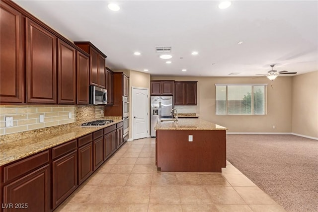 kitchen with an island with sink, tasteful backsplash, visible vents, appliances with stainless steel finishes, and open floor plan