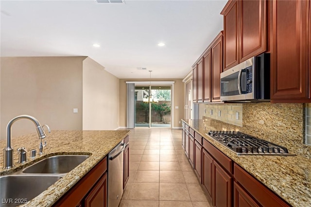 kitchen featuring light tile patterned floors, reddish brown cabinets, a sink, stainless steel appliances, and backsplash