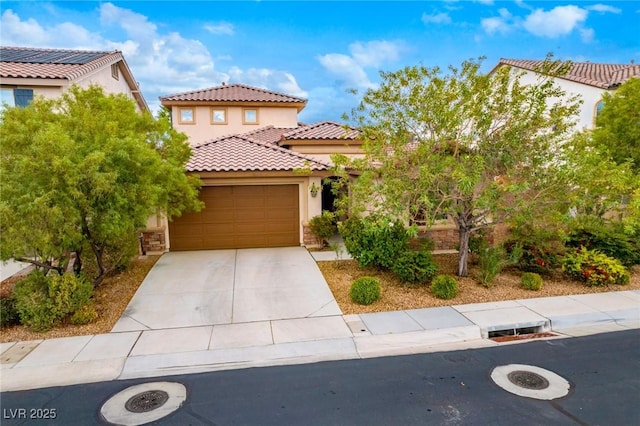 mediterranean / spanish home with a tiled roof, an attached garage, concrete driveway, and stucco siding