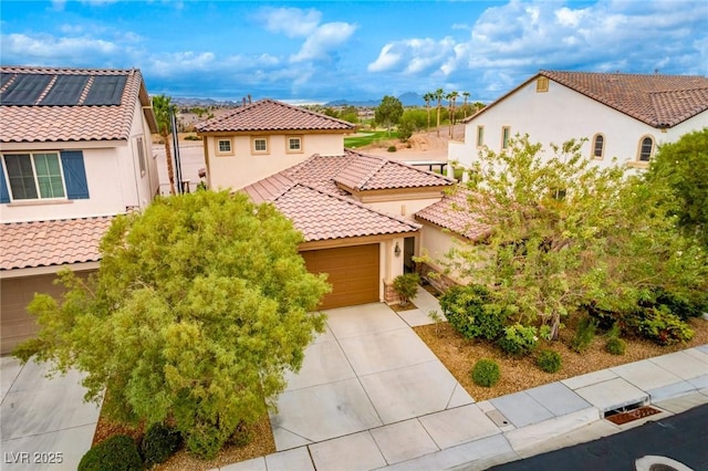 mediterranean / spanish-style house with concrete driveway, a residential view, stucco siding, a tile roof, and a garage