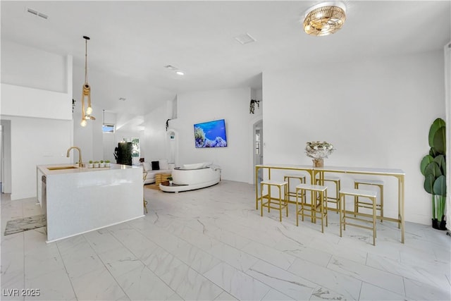 9155 Bush Poppy Ave, Las Vegas, NV 89147 - kitchen featuring marble look tiles, vaulted ceiling, an island with sink, a sink, and open floor plan