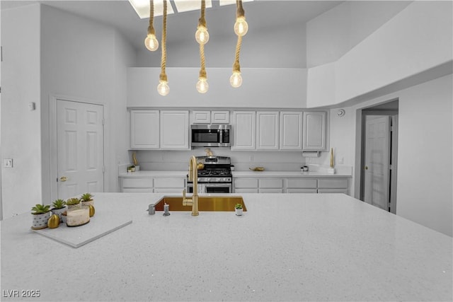 9155 Bush Poppy Ave, Las Vegas, NV 89147 - kitchen featuring stainless steel appliances, high vaulted ceiling, a sink, light stone countertops, and hanging light fixtures