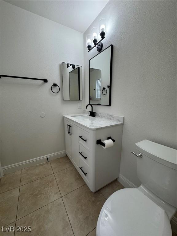 bathroom featuring toilet, baseboards, tile patterned flooring, and vanity