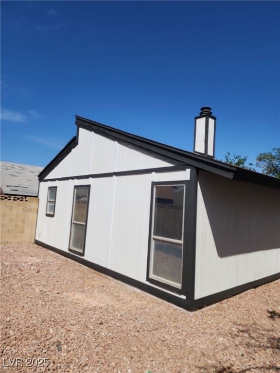 view of side of property with fence and a chimney