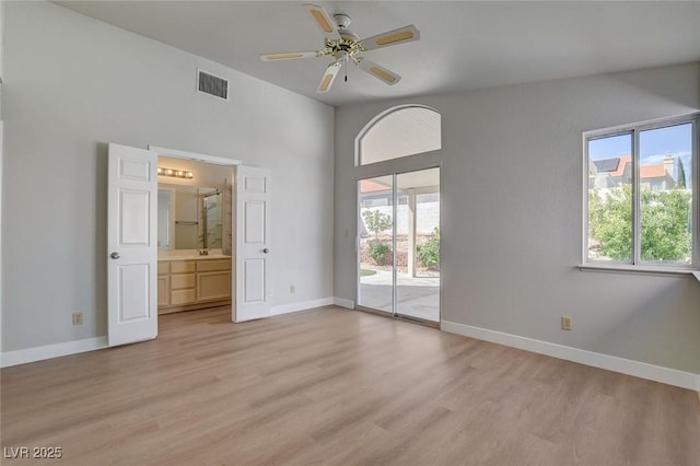 empty room with light wood-style floors, visible vents, baseboards, and a ceiling fan