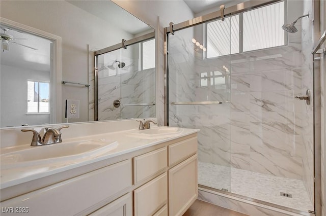 bathroom with double vanity, a sink, a marble finish shower, and ceiling fan