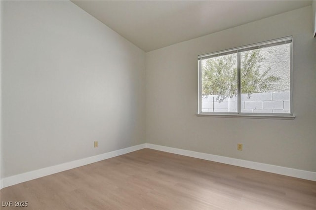 unfurnished room featuring light wood-style flooring, vaulted ceiling, and baseboards