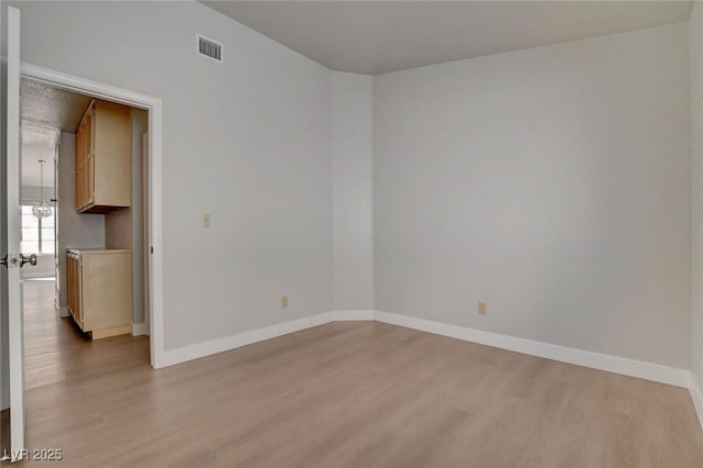 unfurnished room featuring visible vents, baseboards, and wood finished floors