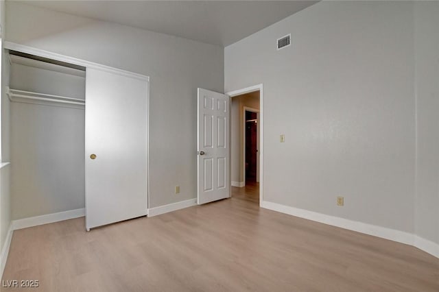 unfurnished bedroom with a closet, visible vents, baseboards, and wood finished floors