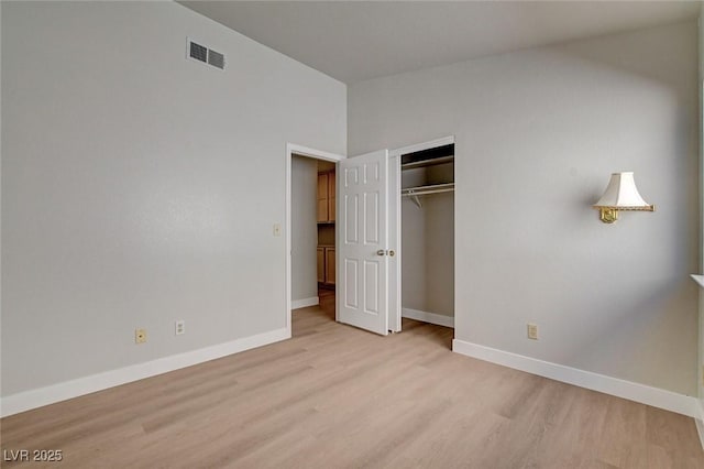 unfurnished bedroom featuring light wood-style floors, a closet, baseboards, and visible vents