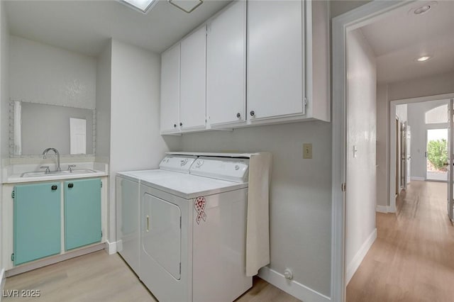 laundry area with baseboards, washer and dryer, a sink, light wood finished floors, and cabinet space