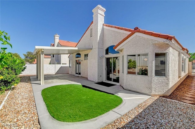 rear view of house with a tiled roof, stucco siding, a patio, fence, and a chimney