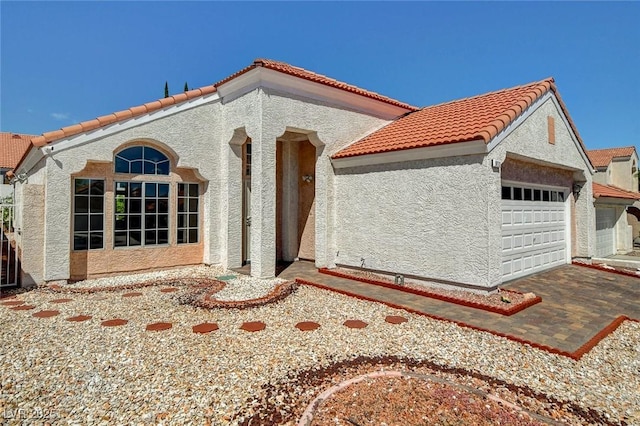 mediterranean / spanish-style home featuring a garage, stucco siding, and a tile roof