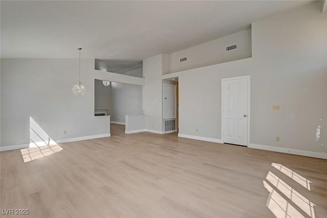 unfurnished living room with visible vents, baseboards, and high vaulted ceiling