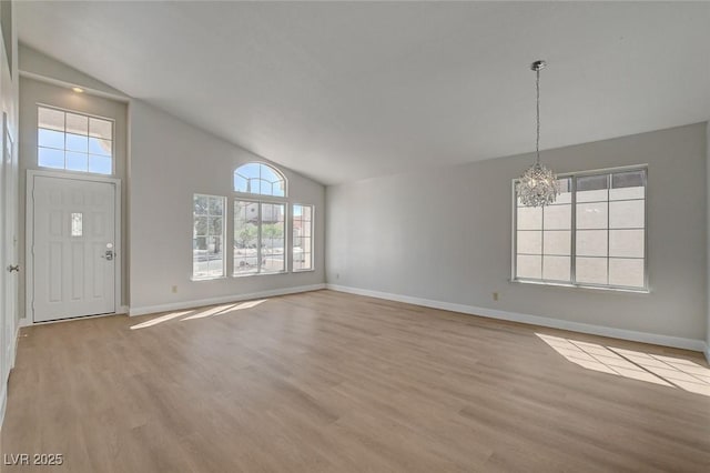 interior space featuring baseboards, a wealth of natural light, an inviting chandelier, and wood finished floors