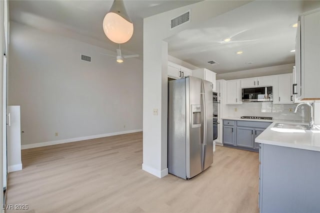 kitchen with light wood-style floors, appliances with stainless steel finishes, a sink, and visible vents