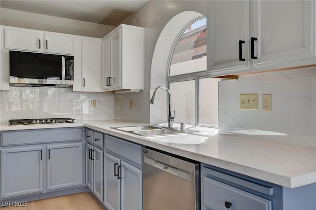 kitchen featuring gray cabinets, appliances with stainless steel finishes, decorative backsplash, and a sink