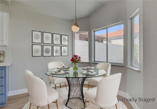dining space featuring baseboards, vaulted ceiling, and wood finished floors