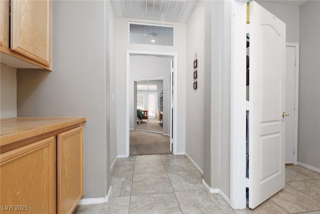hallway with visible vents, baseboards, and light tile patterned flooring