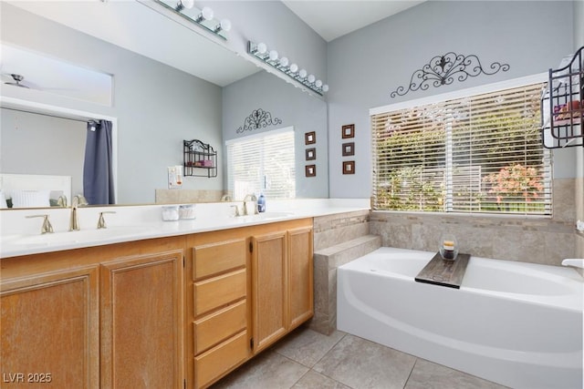 full bathroom featuring a bath, tile patterned floors, double vanity, and a sink