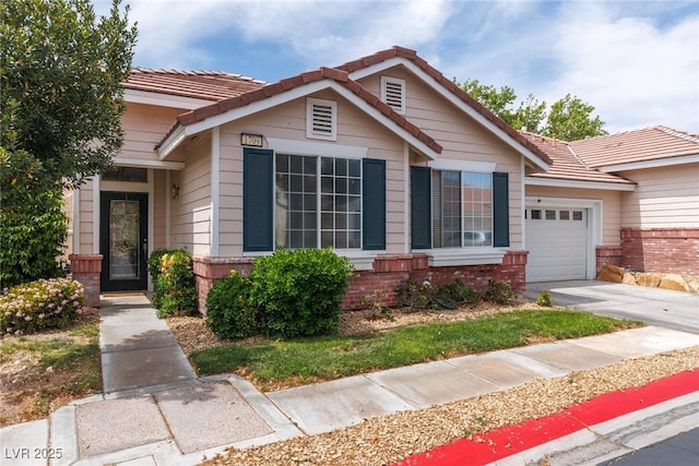 view of front of house with a garage, brick siding, concrete driveway, and a tile roof