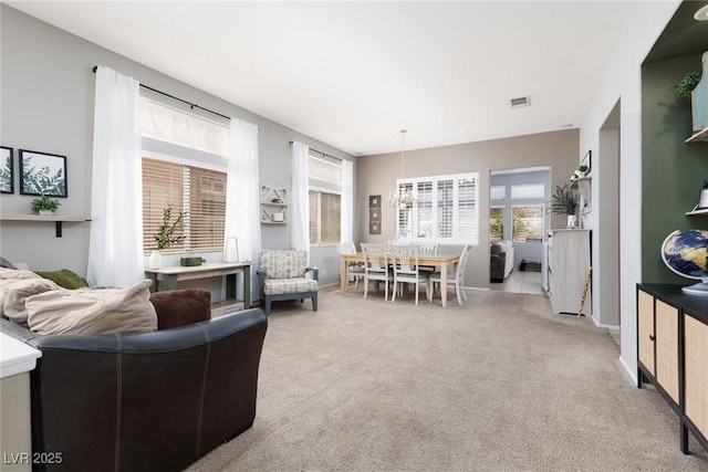 living area with a chandelier, carpet flooring, baseboards, and a healthy amount of sunlight