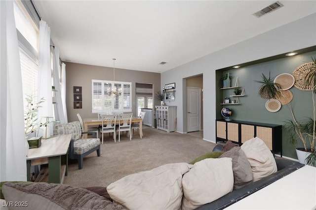 living area featuring radiator, carpet flooring, a notable chandelier, and visible vents