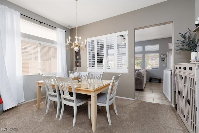 carpeted dining area with a chandelier and baseboards