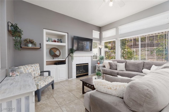 living area featuring built in features, ceiling fan, light tile patterned flooring, and a fireplace