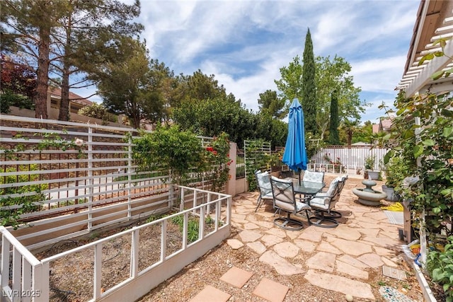 view of patio with a garden, outdoor dining area, and fence