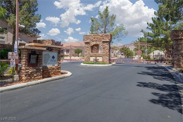view of street featuring a gated entry, curbs, and a gate