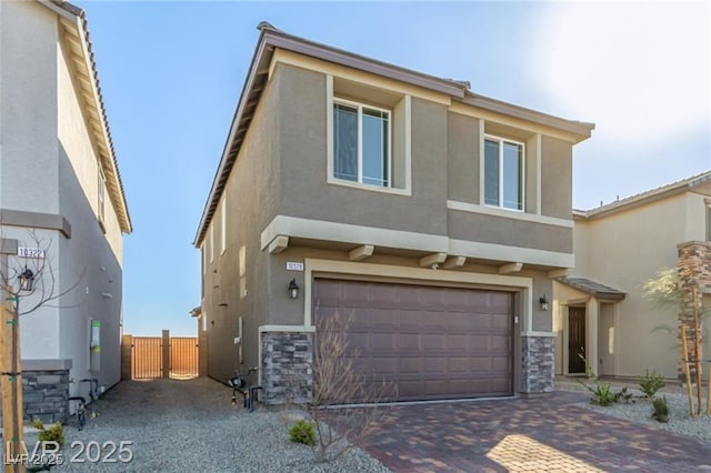 view of front of property with an attached garage, stucco siding, decorative driveway, and a gate
