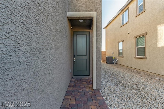 entrance to property with central air condition unit and stucco siding