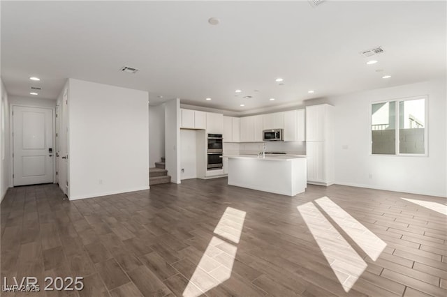 unfurnished living room featuring recessed lighting, visible vents, stairs, and wood finished floors