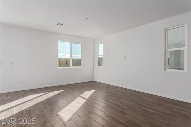 unfurnished room with baseboards, dark wood finished floors, and visible vents
