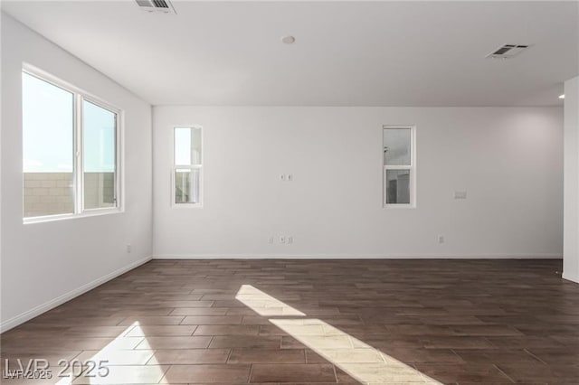 spare room with baseboards, dark wood finished floors, and visible vents