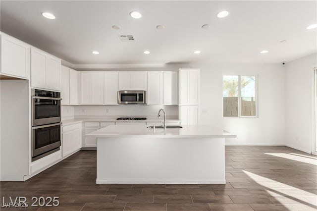 kitchen featuring an island with sink, visible vents, light countertops, a sink, and stainless steel appliances