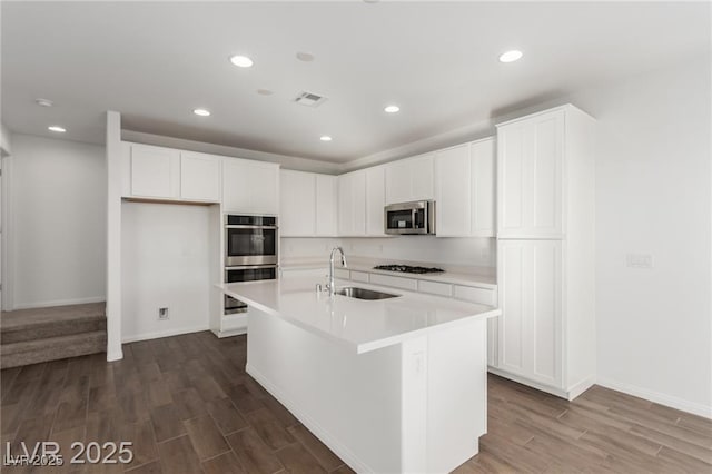 kitchen with dark wood finished floors, light countertops, a sink, stainless steel appliances, and baseboards