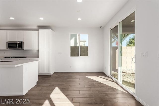 kitchen with stainless steel microwave, dark wood-type flooring, baseboards, and a healthy amount of sunlight
