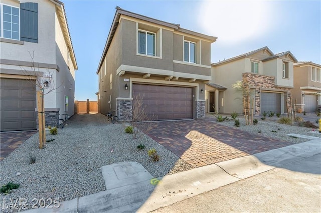traditional-style home featuring an attached garage, stucco siding, stone siding, and decorative driveway