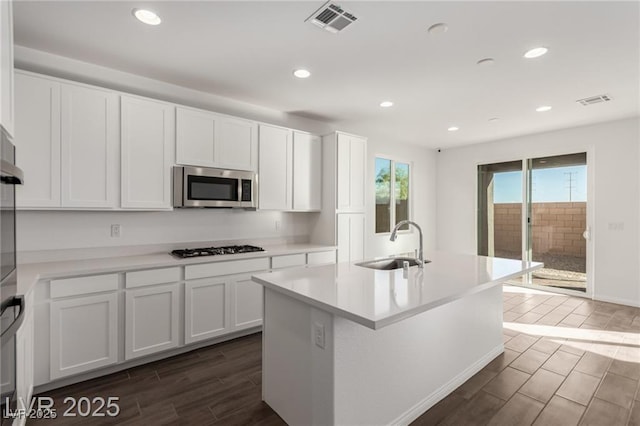 kitchen featuring visible vents, a sink, gas stovetop, wood tiled floor, and stainless steel microwave