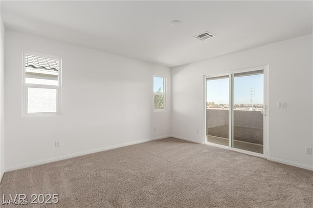spare room featuring carpet floors, visible vents, and baseboards