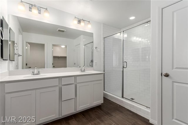 bathroom with a shower stall, wood finished floors, a sink, and visible vents