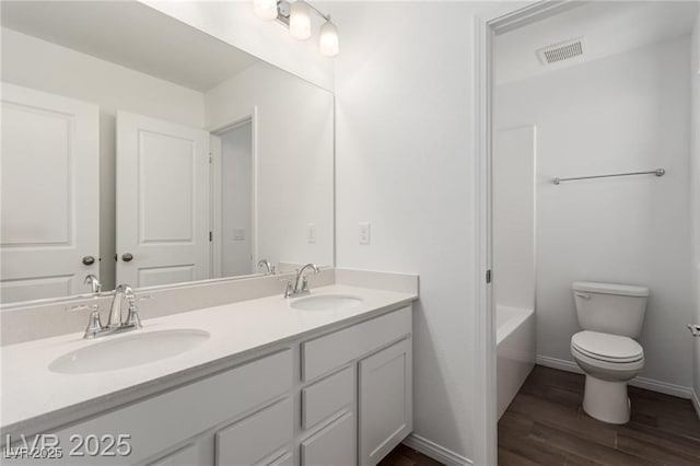 full bathroom with wood finished floors, visible vents, a sink, and toilet