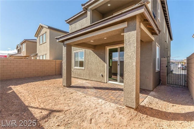rear view of house with fence, a patio, and stucco siding